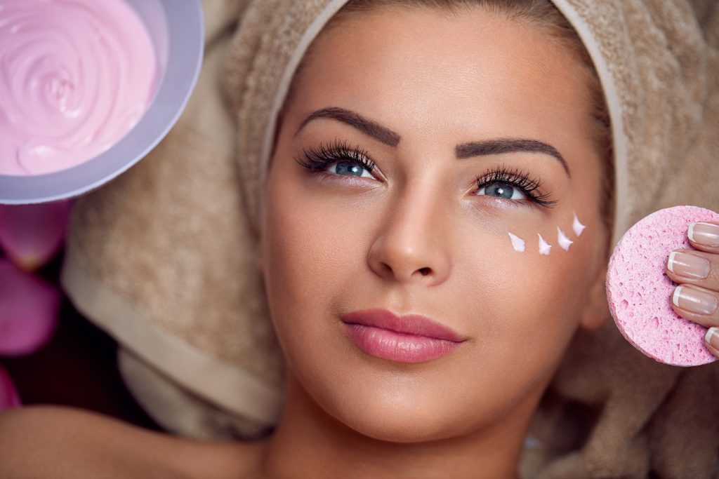 Pretty young woman with facial mask at beauty salon